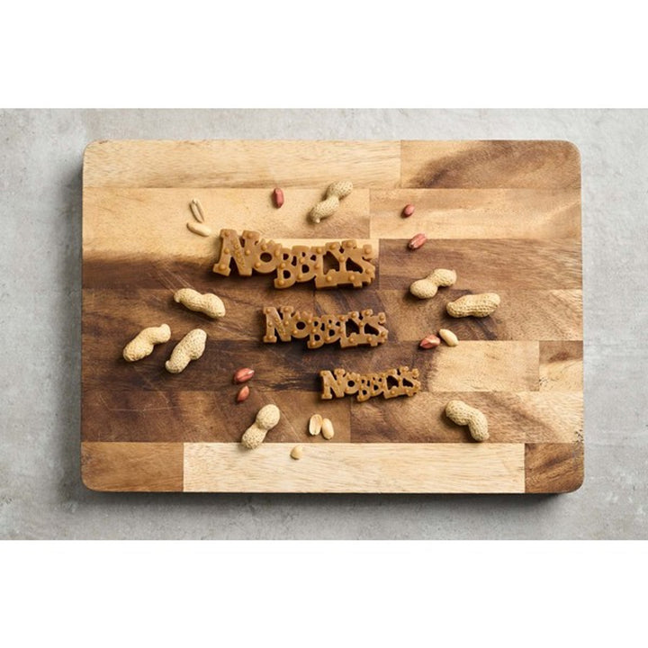 Petello nobblys peanut butter chew on a wooden board with but around 